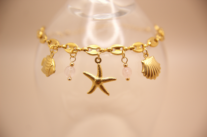 Pink Tide Bracelet in gold with starfish, shell, fish, and pink stone charms
