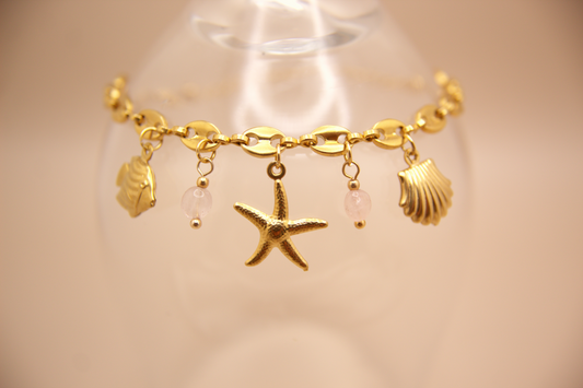 Pink Tide Bracelet in gold with starfish, shell, fish, and pink stone charms