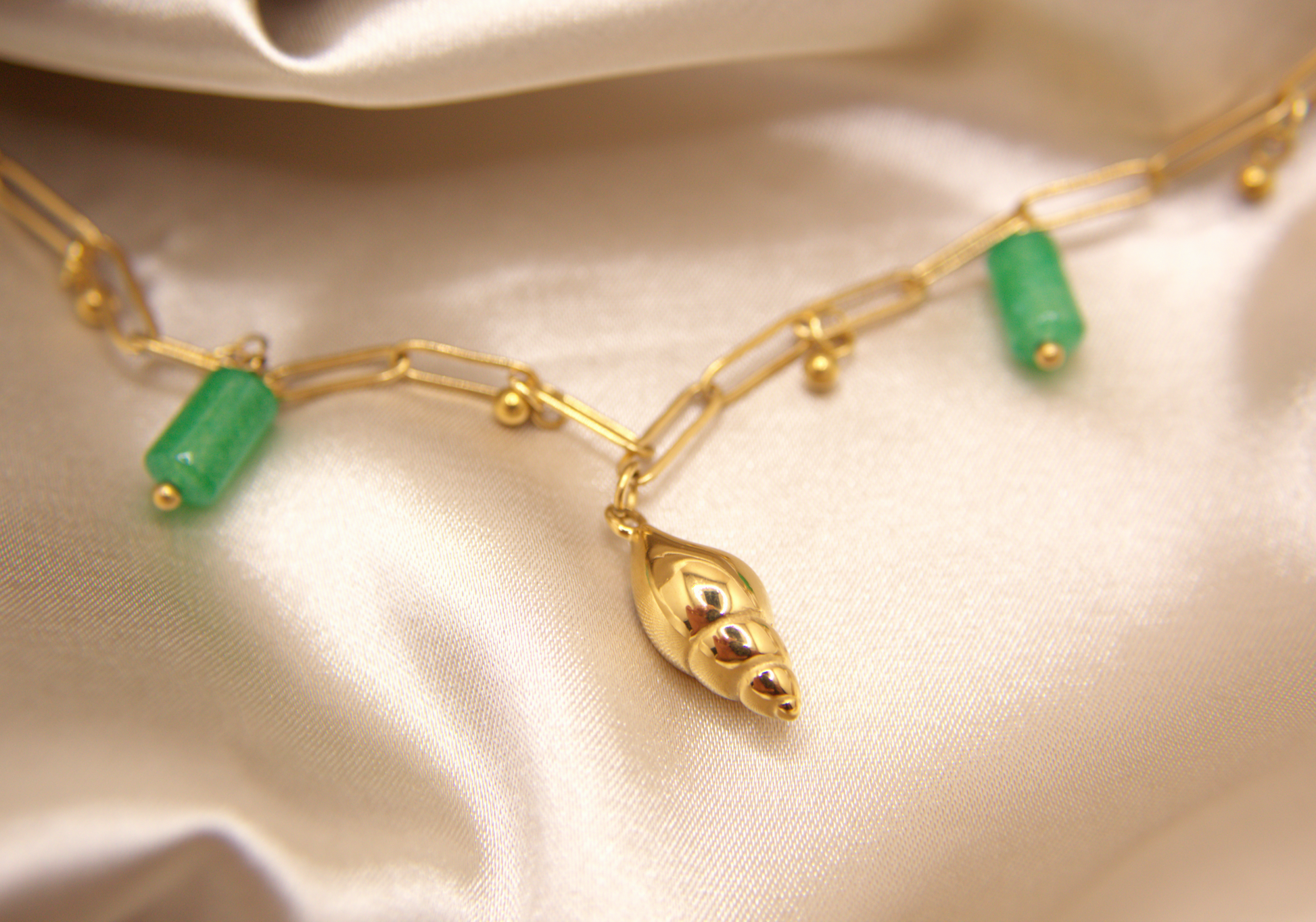 Sea Gem Bracelet in gold with snail charm, green stones, and golden beads