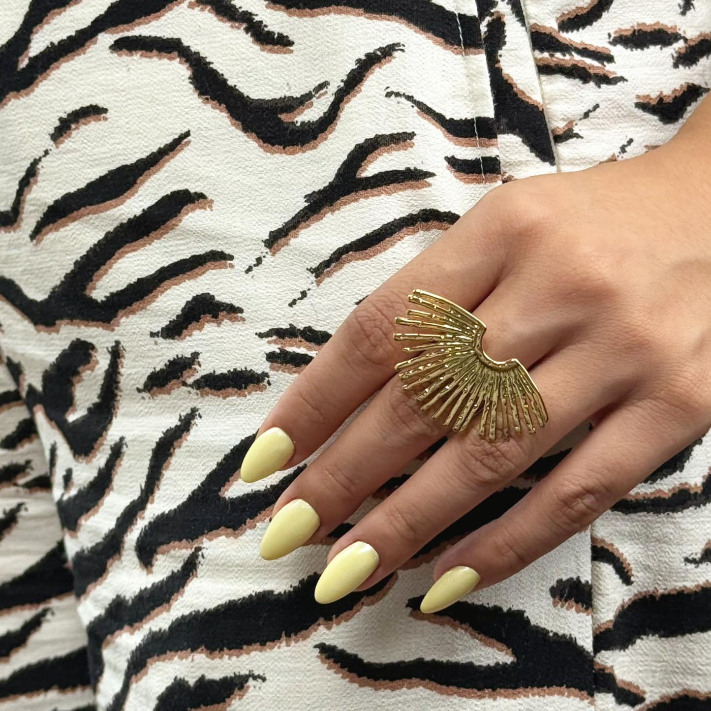 Golden fan-shaped ring with organic texture and tropical design.