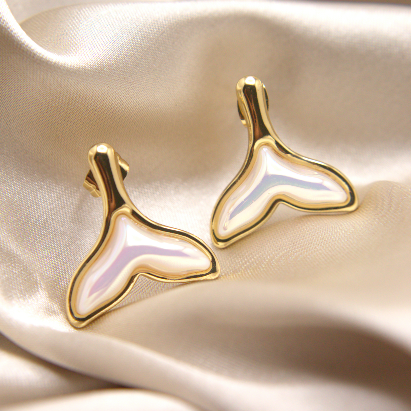 Ocean-style gold studs shaped like a whale tail with nacre shine.