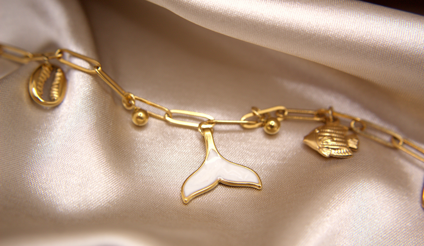 Siren’s Whisper Bracelet in gold with white enamel mermaid tail, fish, and shell charms
