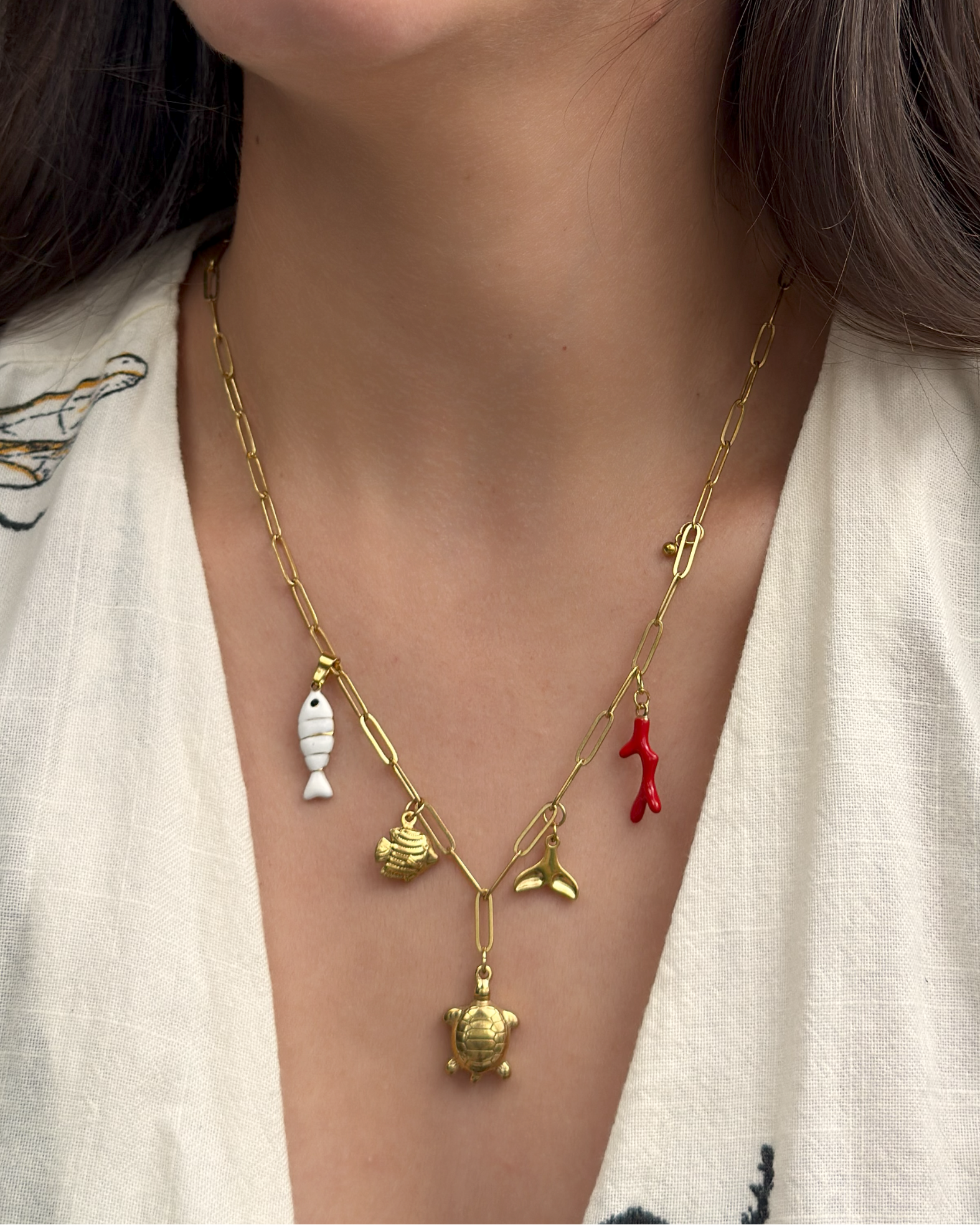 Gold ocean-inspired necklace featuring whale tail and red coral charm