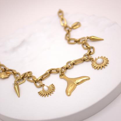 Beach-inspired gold link necklace with white stone and whale tail pendant